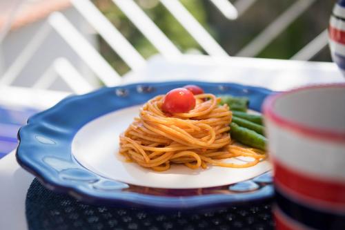 a plate of pasta and vegetables on a table with a drink at Positamy in Positano