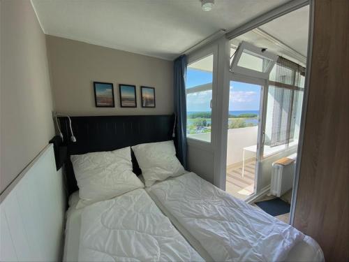 ein kleines Schlafzimmer mit einem Bett und einem Balkon in der Unterkunft Ferienpark H07-011 Ferienpark in Heiligenhafen