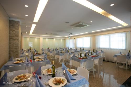 um salão de banquetes com mesas brancas e cadeiras brancas em HOTEL NARCISi2 em Roseto degli Abruzzi