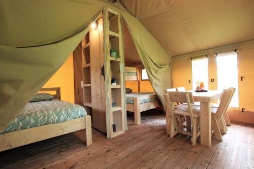 ein Schlafzimmer mit einem Bett und einem Tisch in einem Zelt in der Unterkunft TENTE SAFARI Lodge FERME CARRIQUE in Tardets-Sorholus