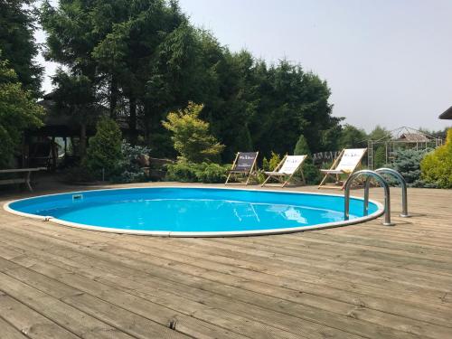 a swimming pool with two chairs in a yard at Bieszczadzkie Chatki - Willa Stasia in Ustrzyki Dolne