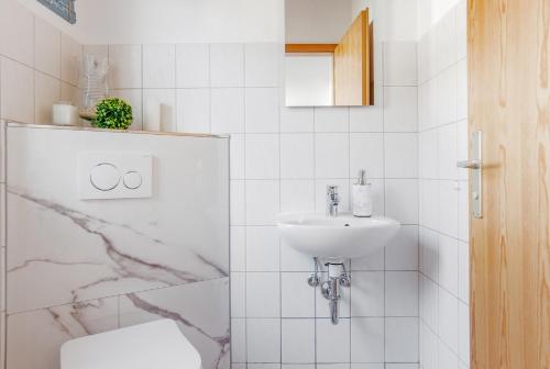 a white bathroom with a sink and a toilet at Sünnhus in Heiligenhafen
