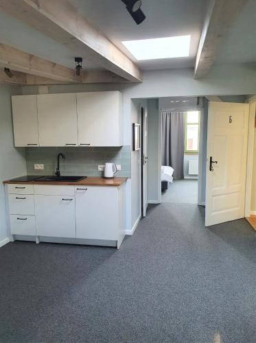 a kitchen with white cabinets and a room with a bed at Apartamenty K17 Centrum in Malbork