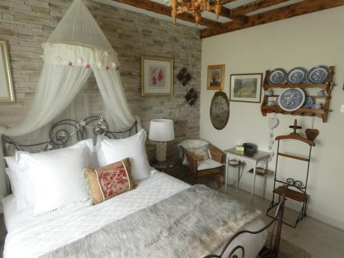 een slaapkamer met een wit bed en een bakstenen muur bij Bunratty Castle Mews B&B in Bunratty