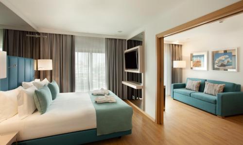 a hotel room with a large bed and a blue couch at TURIM Presidente Hotel in Portimão