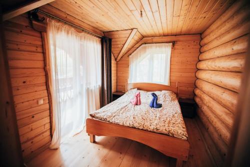 ein Bett in einem Holzzimmer mit zwei Schuhen darauf in der Unterkunft Гостинний двір Гуцулка in Scheschory
