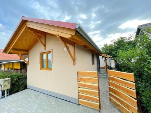 una pequeña casa con una valla de madera alrededor en Ibolya Apartman, en Csisztapuszta