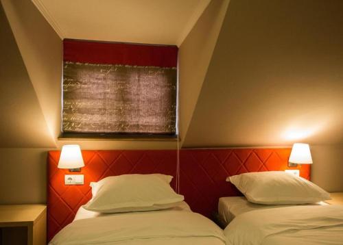 two beds in a room with a red headboard at CASA GRINDA in Sibiu