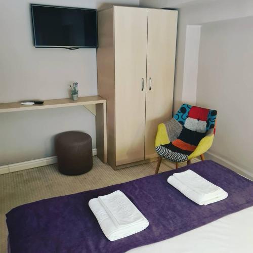 a room with a bed and a chair and a tv at CASA GRINDA in Sibiu