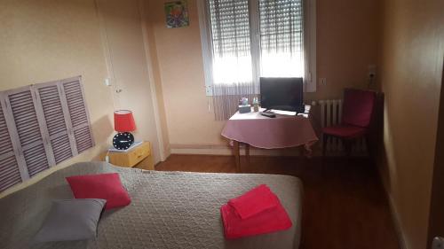 a bedroom with a bed with red pillows and a desk at HOTEL RESTAURANT Bar LA KAHINA in Chouzé-sur-Loire