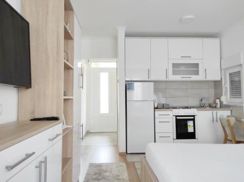 een keuken met witte kasten en een witte koelkast bij Apartment SUNSET in Trebinje