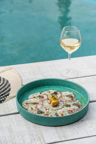 a bowl of food and a glass of wine on a table at Rigas Boutique Hotel & Spa in Afitos