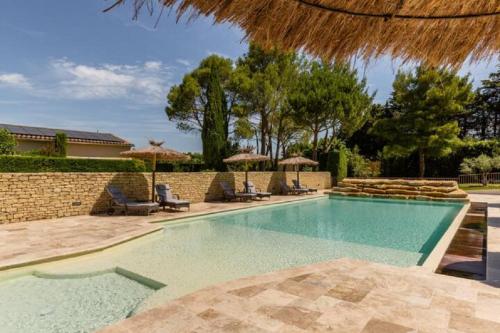 une piscine avec chaises et parasols dans l'établissement La Bastide de l Etang, à LʼIsle-sur-la-Sorgue