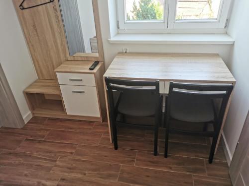 uma pequena cozinha com uma mesa de madeira e cadeiras pretas em Reda apartments em Lublin