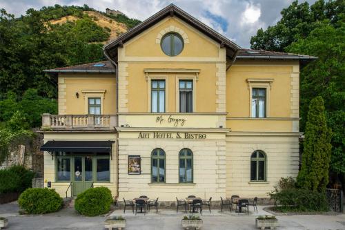 a building with tables and chairs in front of it at Mr Görgey Art Hotel & Spa in Visegrád