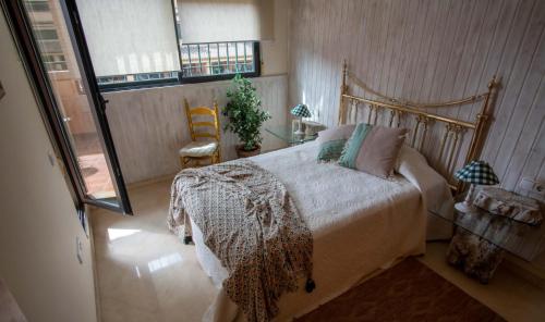 a bedroom with a bed and a chair and a window at Casa MUNDOVALENCIA in Valencia