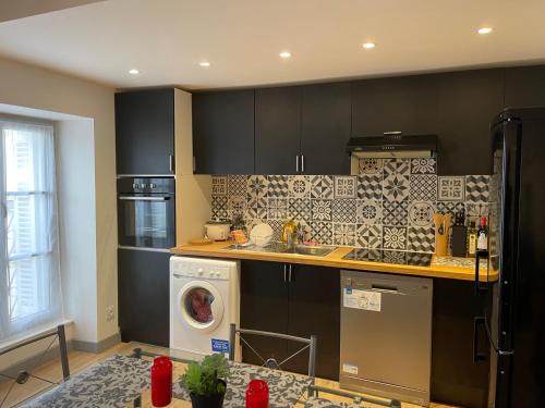 - une cuisine avec des armoires noires et un lave-linge dans l'établissement BORDEAUX CENTRE BELLE DUPLEX, à Bordeaux
