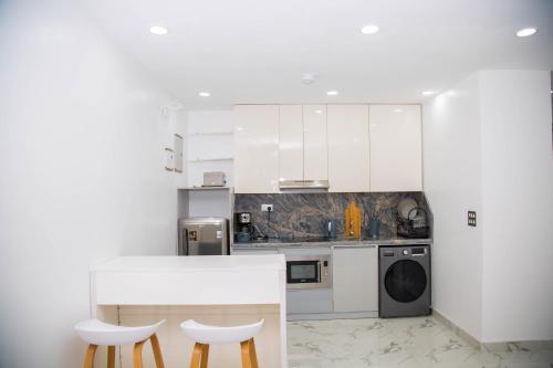 a kitchen with white cabinets and a table and two stools at MiVi - Midtown Victoria Island in Lagos