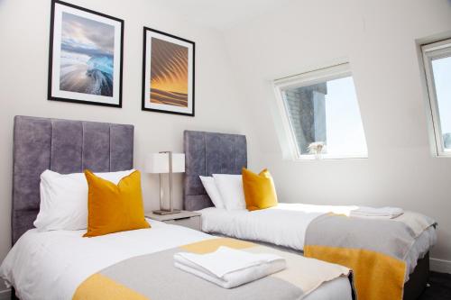 1 Schlafzimmer mit 2 Betten mit orangefarbenen und grauen Kissen in der Unterkunft High Life Serviced Apartments - Old Town in Swindon