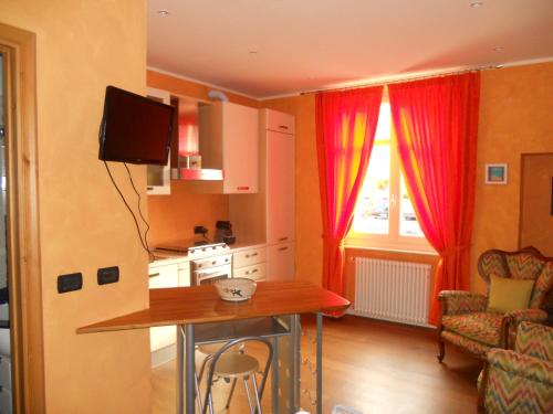 Tagliolo MonferratoにあるIl Cedroの赤いカーテンとテーブル付きのキッチンが備わります。