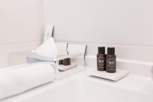 a white counter with two bottles of hair products at Hotel Brandenburger Tor Potsdam in Potsdam