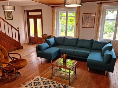 a living room with a blue couch and a table at Grande maison escapade au bord de la riviere in Touvre