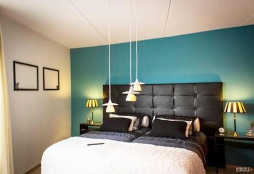 1 dormitorio con 1 cama grande y pared azul en Studio PolderPoort, en Kampen