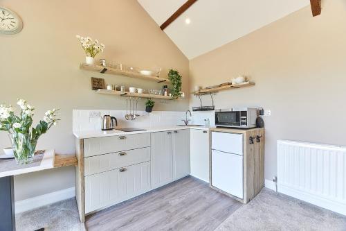 a kitchen with white cabinets and a microwave at Host & Stay - The Pepper Pot in Alnwick