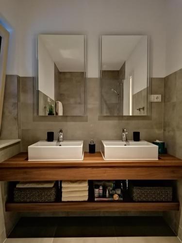 two sinks in a bathroom with two mirrors at Villa NOVAMARIN - heated pool, sauna, garden in Drage