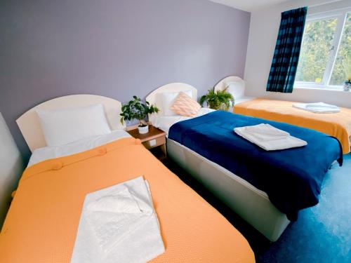 two beds in a room with orange and blue at Redwings Lodge Baldock in Baldock