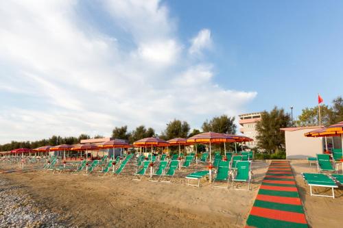 um grupo de cadeiras e guarda-sóis numa praia em HOTEL NARCISi2 em Roseto degli Abruzzi