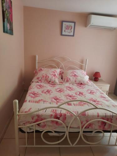 - un lit avec une couette et des oreillers roses et blancs dans l'établissement CHAMBRE LEUCATE VILLAGE, à Leucate