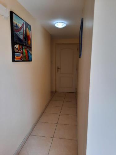un couloir avec une porte et un sol carrelé dans l'établissement CHAMBRE LEUCATE VILLAGE, à Leucate