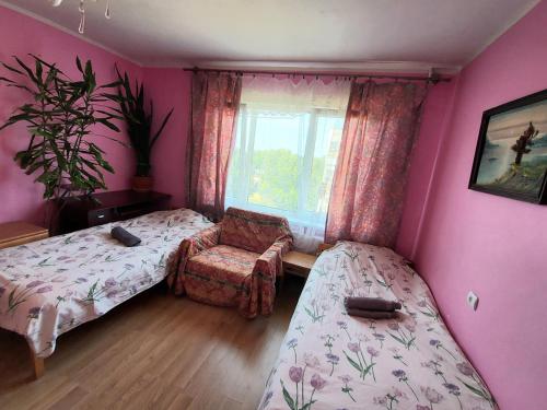 1 dormitorio con 2 camas, silla y ventana en Отдельная комната в Юрмале, en Jūrmala