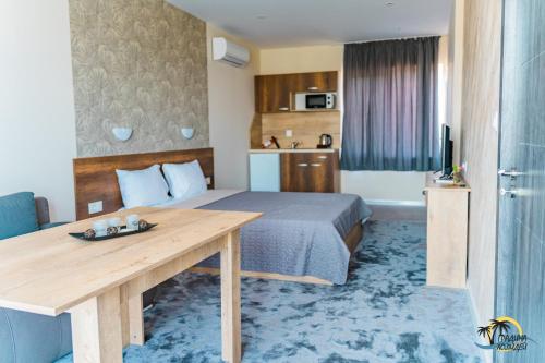 ソゾポルにあるGradina Holidayのベッドと木製テーブルが備わるホテルルームです。