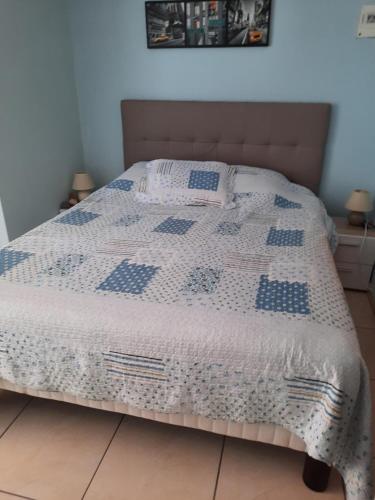 - un lit avec une couette bleue et blanche dans l'établissement CHAMBRE A LEUCATE VILLAGE, à Leucate