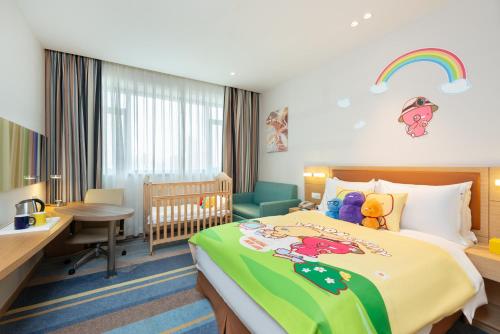 a hotel room with a bed and a desk and a crib at Holiday Inn Express Shanghai Zhenping by IHG in Shanghai
