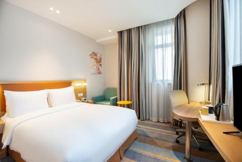 a hotel room with a bed and a desk and a television at Holiday Inn Express Shanghai Zhenping by IHG in Shanghai