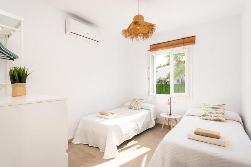a white room with two beds and a window at Villa Menorca ROCAS by Mauter Villas in Cala en Bosc