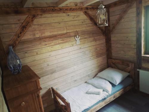 uma pequena cama num quarto com uma parede de madeira em Domek Na Gwizdówce " u KARGULA" - KASZUBY em Sierakowice