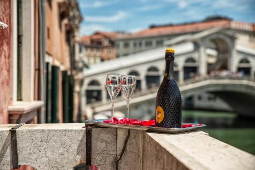 a bottle of champagne and two wine glasses on a ledge at Royal Rialto Apartment - Grand Canal View in Venice