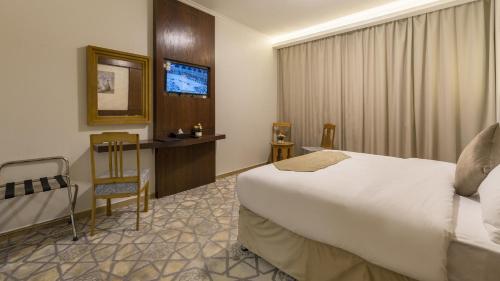 a hotel room with a bed and a television at Jiwar Al Madina Hotel in Al Madinah