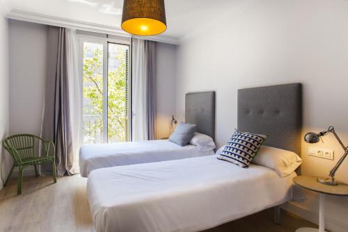 two beds in a room with a window at Ola Living Broto in Barcelona