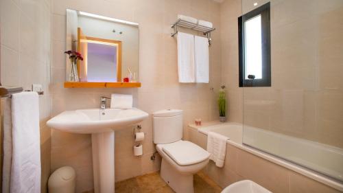 een witte badkamer met een wastafel, een toilet en een bad bij Leo Enebrales in Punta Umbría