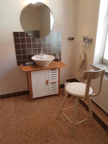 a bathroom with a sink and a chair and a mirror at Modernes wohnen im alten Beelitz Wohnung 1 in Beelitz