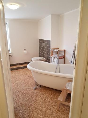 een badkamer met een wit bad en een toilet bij Modernes wohnen im alten Beelitz Wohnung 1 in Beelitz