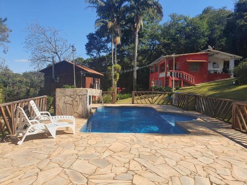 a swimming pool with a chair and a house at Chácara - Usina Atibaia in Atibaia