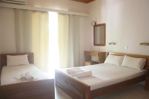 a bedroom with two beds with towels and a mirror at MARIA STUDIOS LAGANAS in Laganas