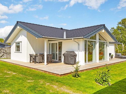 a small white house with a wooden deck at 7 person holiday home in Slagelse in Slagelse