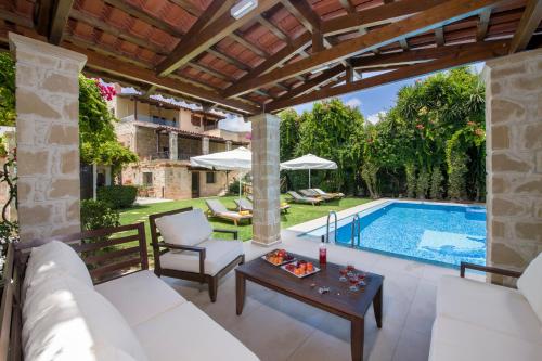 un patio esterno con un divano bianco e un tavolo accanto alla piscina di Villa Arhontariki a Kíssamos